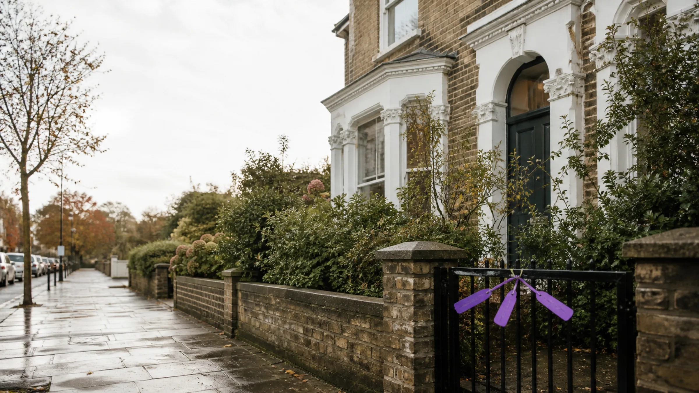 A leafy British street with a Victorian home behind a garden gate